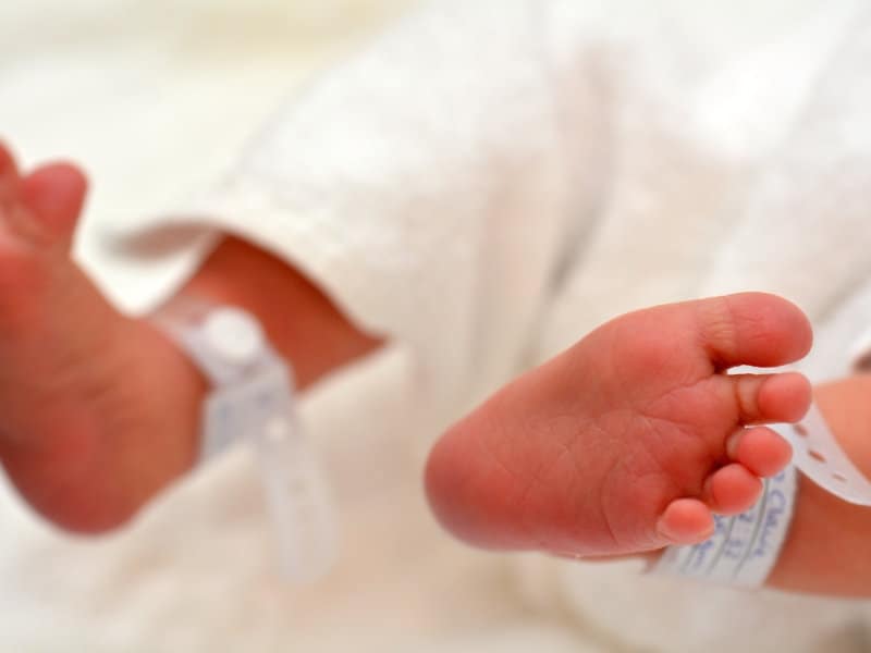 A close up of an RFID tag around the feet of a newborn baby