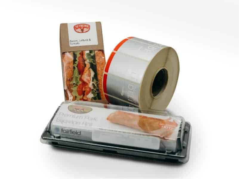 A roll of labels alongside food packaging featuring printed labels