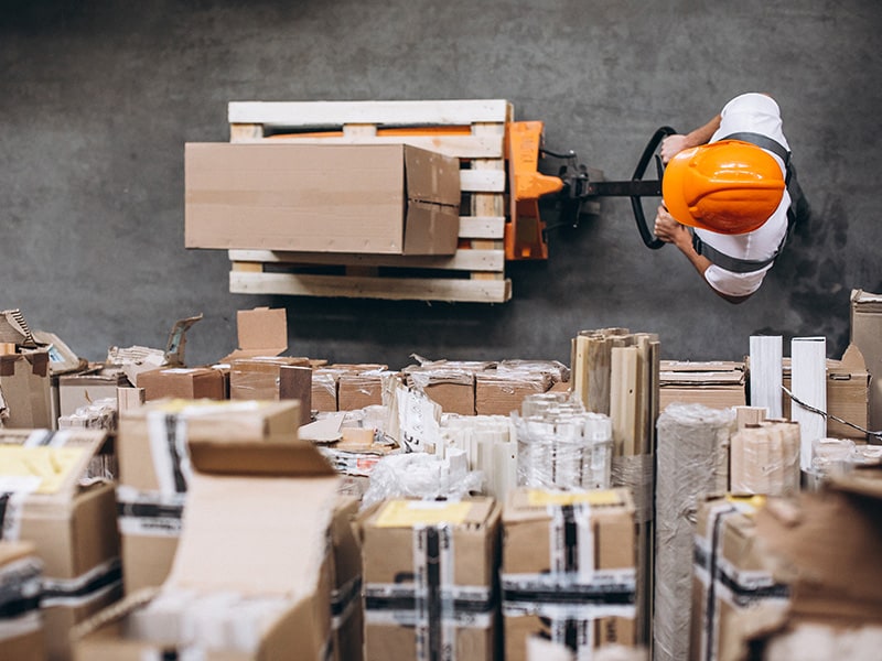 A warehouse worker moving boxes with labels visible